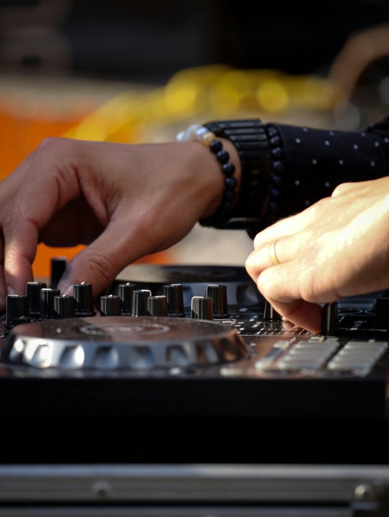 Close-up of a DJ mixing music on professional audio equipment outdoors.