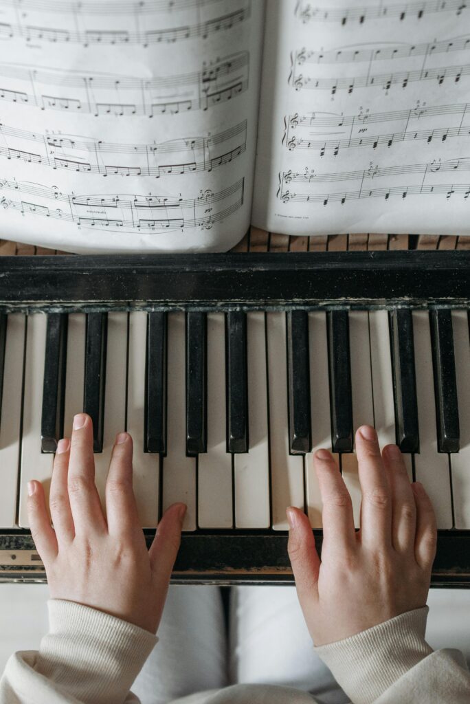 Child playing piano with sheet music above, focusing on hand placement and notes.